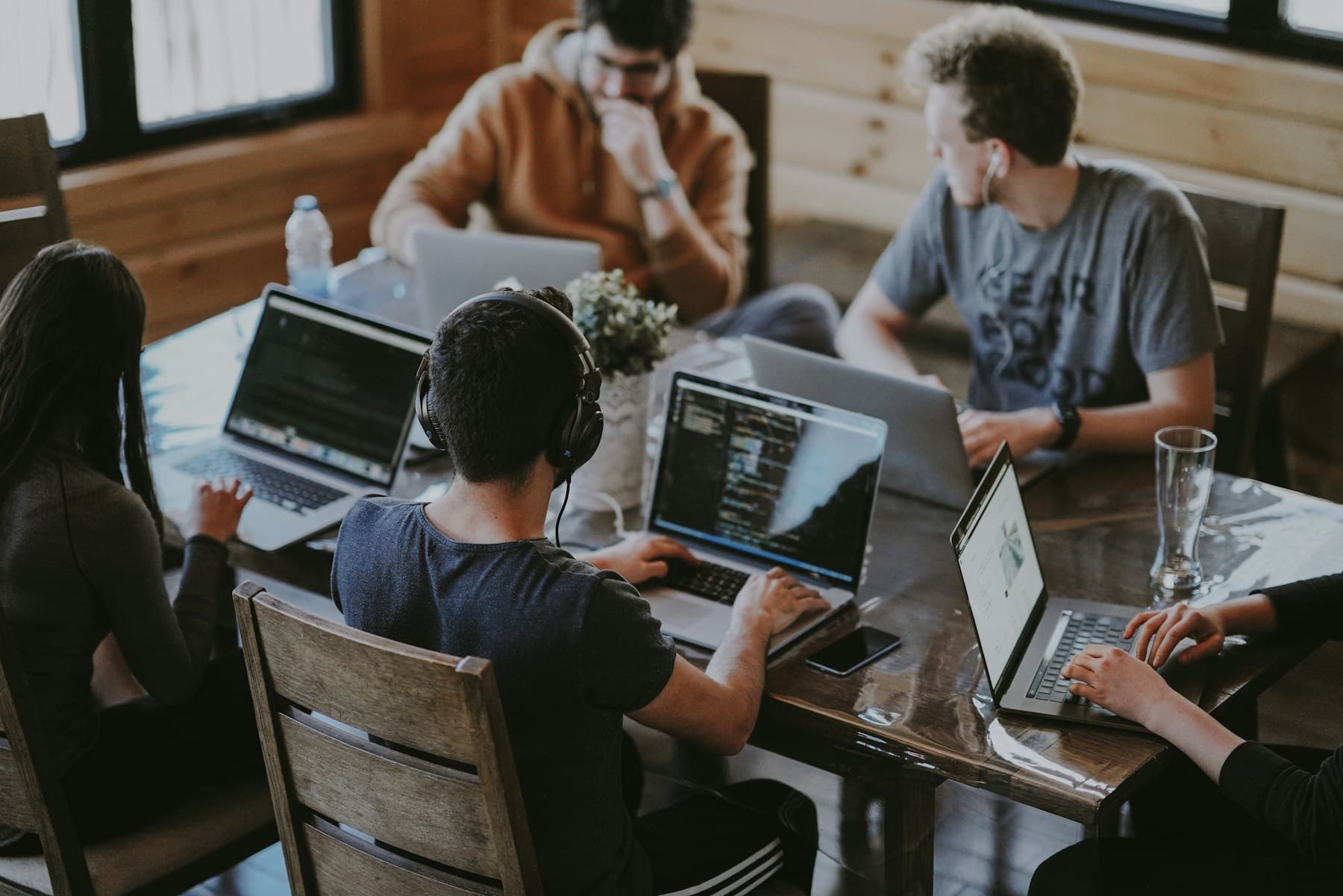 Colleagues working together on laptops around a shared office table.