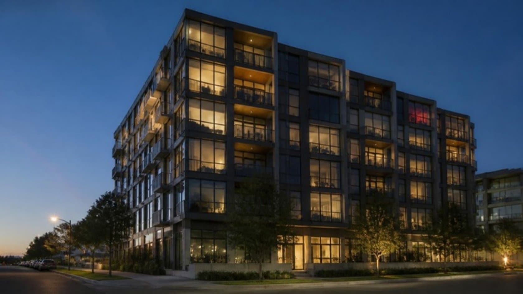 Modern apartment building at dusk with separately lit units under one roof